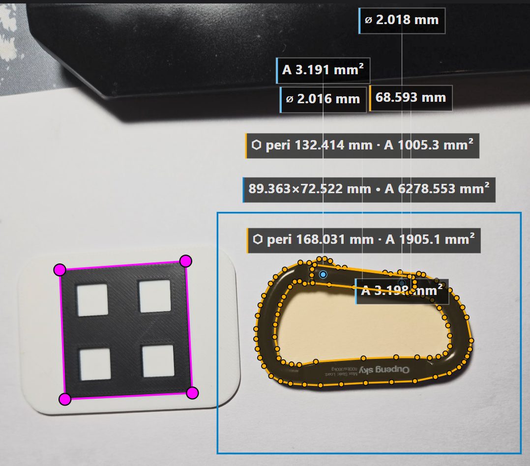 A carabiner photographed next to a printed calibration target, with the measuring tool overlaying outline dimensions in millimetres.